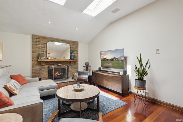 living area featuring vaulted ceiling with skylight, visible vents, a fireplace, baseboards, and wood-type flooring