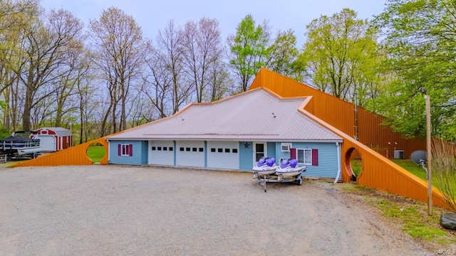 exterior space with central AC, a garage, metal roof, and dirt driveway