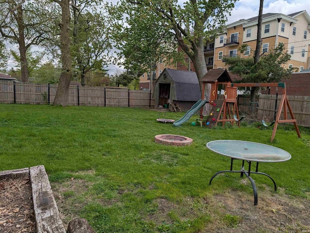 view of yard with an outbuilding, a fenced backyard, a playground, and a storage unit