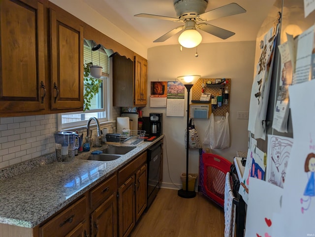 kitchen featuring range with gas stovetop, black dishwasher, tasteful backsplash, a sink, and light wood-style flooring