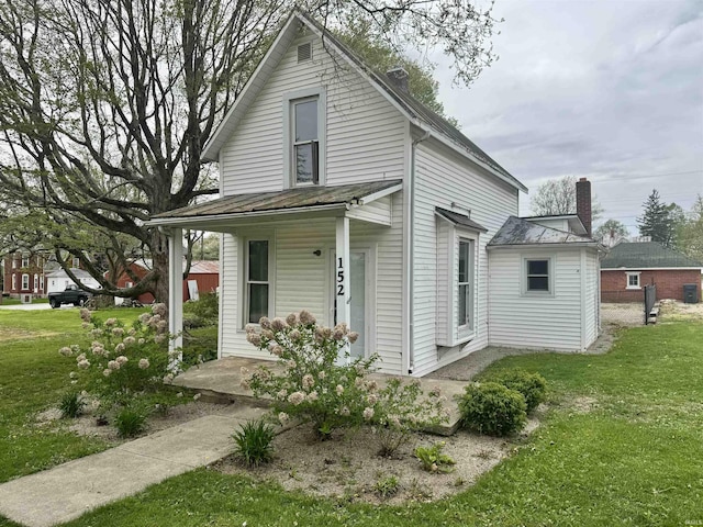 view of home's exterior featuring covered porch, a lawn, and a chimney