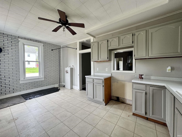kitchen featuring crown molding, ceiling fan, light countertops, baseboards, and light tile patterned floors
