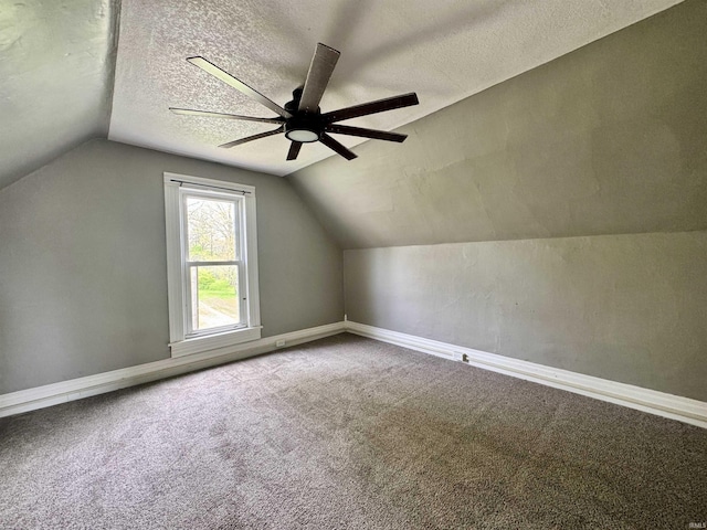 bonus room with ceiling fan, a textured ceiling, baseboards, lofted ceiling, and carpet flooring