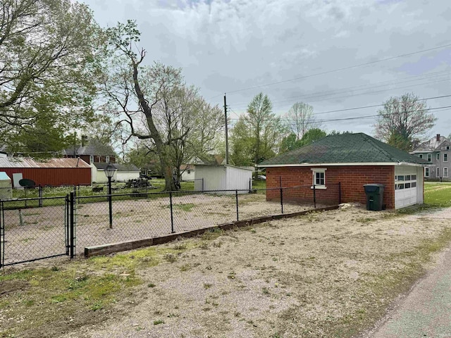 view of yard featuring a gate, fence, an outbuilding, and a detached garage