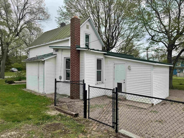 rear view of house with fence, a gate, central AC unit, a chimney, and metal roof