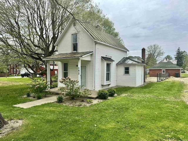 rear view of house featuring covered porch, a lawn, a standing seam roof, and metal roof