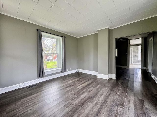 unfurnished room featuring crown molding, baseboards, dark wood-style floors, and visible vents
