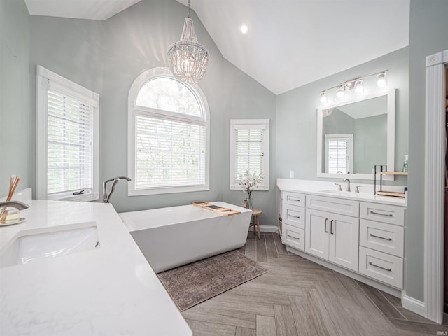 full bathroom with a freestanding bath, vanity, high vaulted ceiling, a chandelier, and baseboards