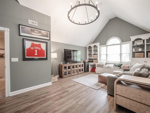 living room with visible vents, wood finished floors, baseboards, high vaulted ceiling, and a notable chandelier