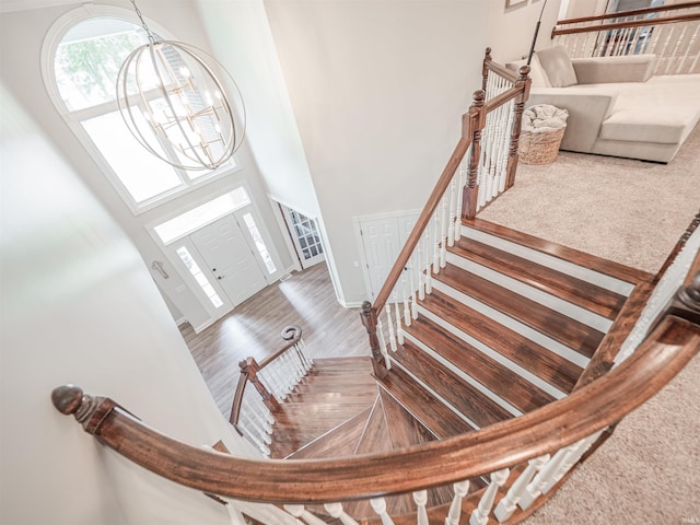 foyer entrance featuring wood finished floors, a chandelier, and a towering ceiling