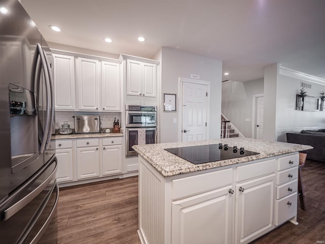 kitchen featuring dark wood-style flooring, a kitchen island, recessed lighting, appliances with stainless steel finishes, and backsplash