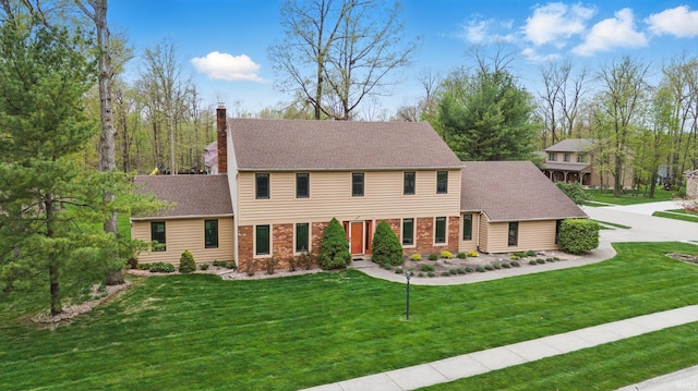 colonial house with roof with shingles, a chimney, and a front lawn