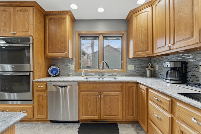kitchen featuring backsplash, light stone countertops, appliances with stainless steel finishes, and a sink
