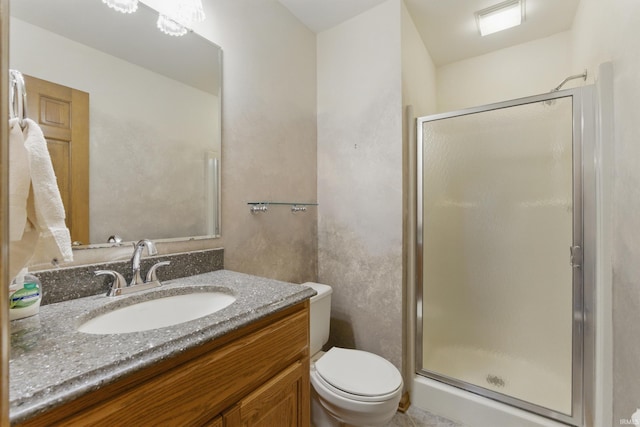 bathroom with vanity, a shower stall, and toilet