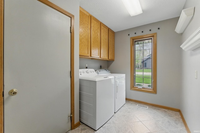 clothes washing area featuring visible vents, baseboards, washing machine and clothes dryer, cabinet space, and light tile patterned floors
