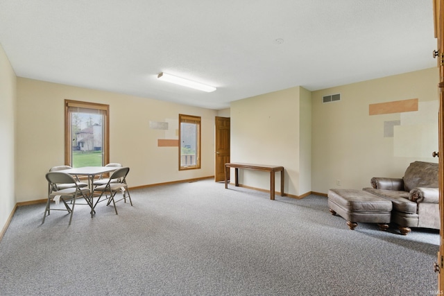 living area with visible vents, baseboards, and light colored carpet