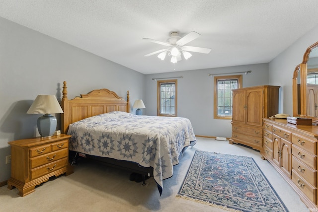 bedroom featuring baseboards, a ceiling fan, a textured ceiling, and light carpet