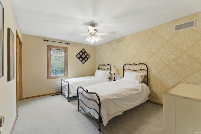 bedroom with a textured ceiling, baseboards, visible vents, and light carpet