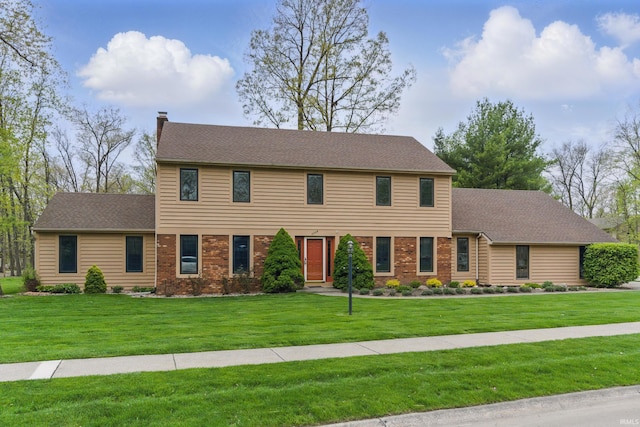 colonial inspired home with brick siding, a front lawn, and a chimney