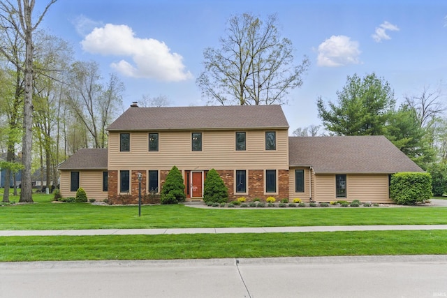 colonial inspired home with a chimney and a front lawn
