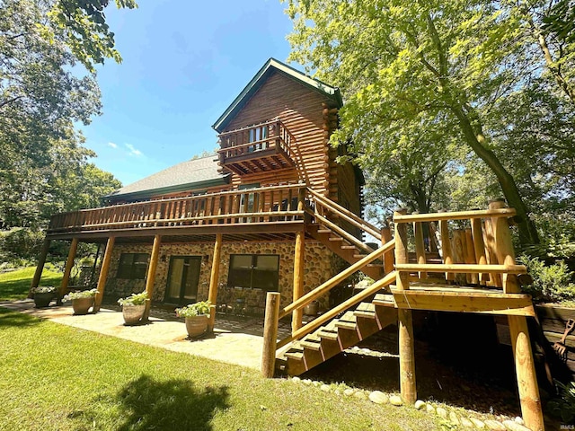 back of house with a lawn, a wooden deck, log exterior, a patio, and stairs