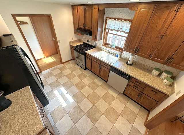 kitchen with a sink, dishwashing machine, stainless steel gas stove, and brown cabinets