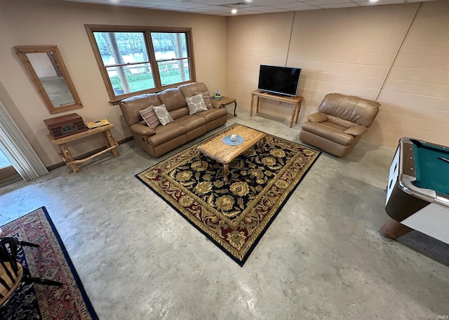 living area with a drop ceiling and unfinished concrete flooring