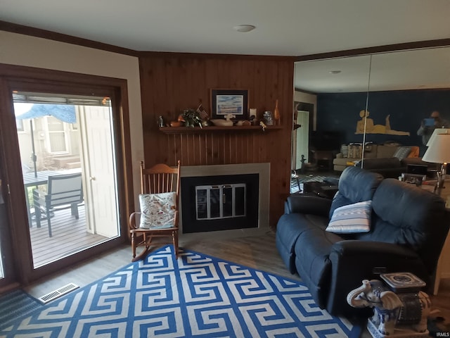 living area with a fireplace, wood walls, wood finished floors, and visible vents