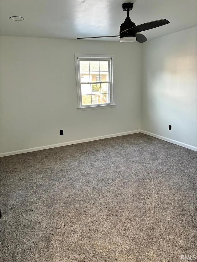 unfurnished room featuring baseboards, ceiling fan, and dark colored carpet