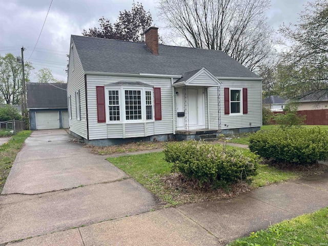 1134 N Iowa St, South Bend, IN 46628 - view of front of house featuring driveway, a chimney, an outbuilding, a detached garage, and a shingled roof