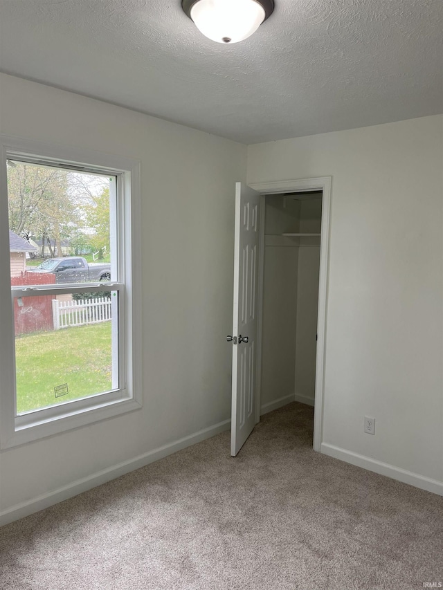 1134 N Iowa St, South Bend, IN 46628 - unfurnished bedroom featuring a textured ceiling, light carpet, baseboards, and a closet