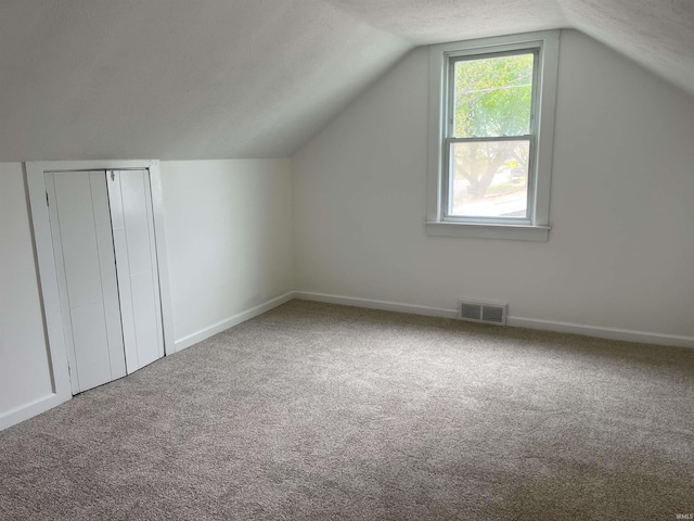 1134 N Iowa St, South Bend, IN 46628 - bonus room featuring a textured ceiling, visible vents, vaulted ceiling, carpet floors, and baseboards