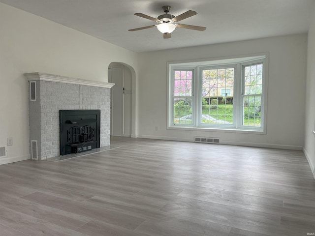 1134 N Iowa St, South Bend, IN 46628 - unfurnished living room featuring ceiling fan, arched walkways, baseboards, wood finished floors, and visible vents