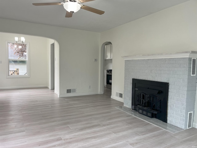 1134 N Iowa St, South Bend, IN 46628 - unfurnished living room featuring arched walkways, ceiling fan with notable chandelier, light wood finished floors, and visible vents