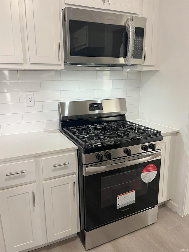 1134 N Iowa St, South Bend, IN 46628 - kitchen featuring white cabinets, stainless steel appliances, and decorative backsplash