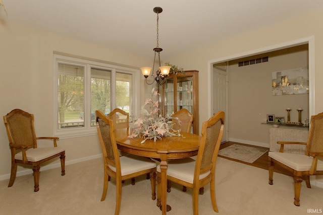 dining room featuring visible vents, baseboards, a chandelier, and light colored carpet
