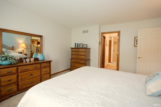 bedroom with visible vents, ensuite bath, and light carpet