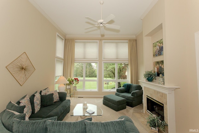 living area with ornamental molding, carpet flooring, ceiling fan, and a tile fireplace