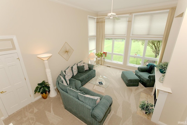 carpeted living area with baseboards, ornamental molding, and ceiling fan