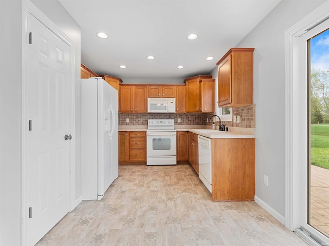 kitchen with a sink, white appliances, light countertops, recessed lighting, and decorative backsplash