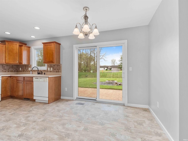 kitchen with white dishwasher, light countertops, brown cabinets, tasteful backsplash, and a notable chandelier