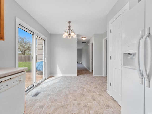 unfurnished dining area featuring an inviting chandelier, light wood-style floors, baseboards, and visible vents