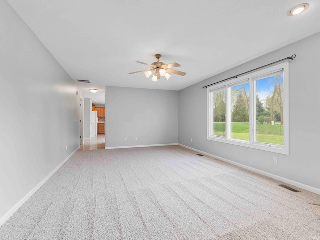 empty room with visible vents, a ceiling fan, baseboards, and carpet