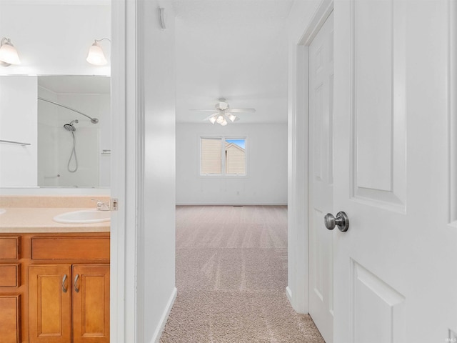 bathroom with vanity, baseboards, ceiling fan, and walk in shower