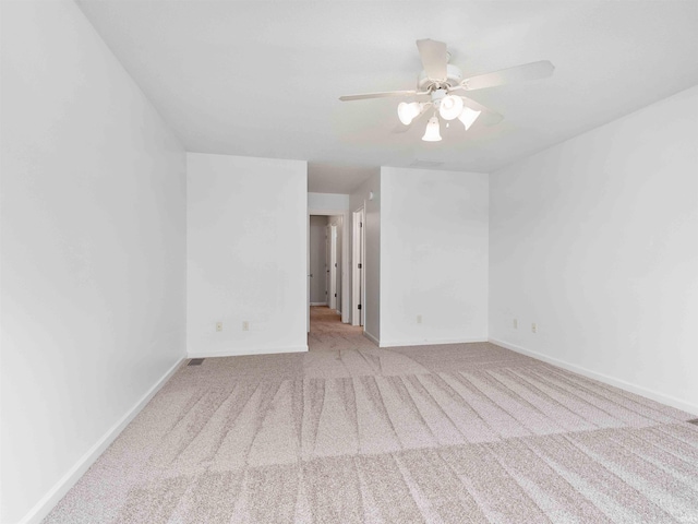 spare room with baseboards, ceiling fan, and carpet