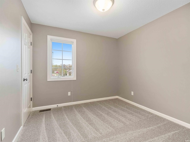 carpeted empty room featuring baseboards and visible vents