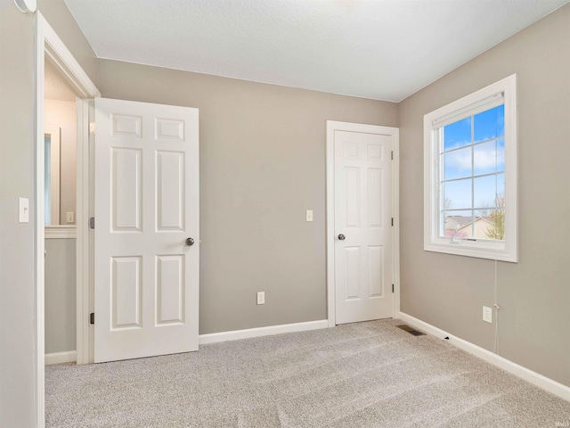 unfurnished bedroom featuring baseboards, carpet flooring, and visible vents