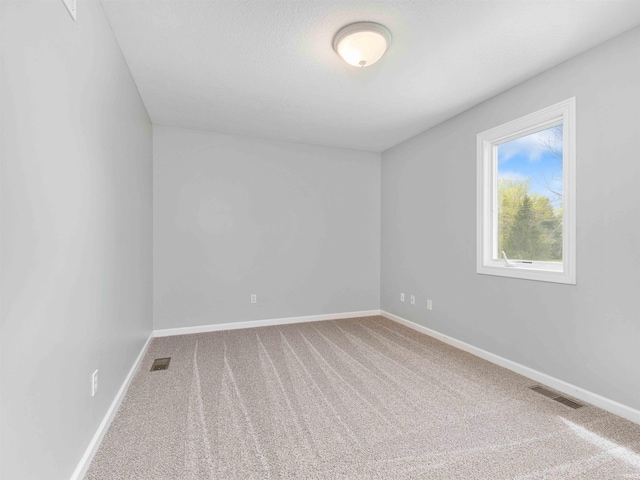 carpeted spare room with visible vents and baseboards