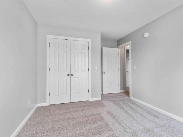 unfurnished bedroom featuring baseboards, carpet, and a closet