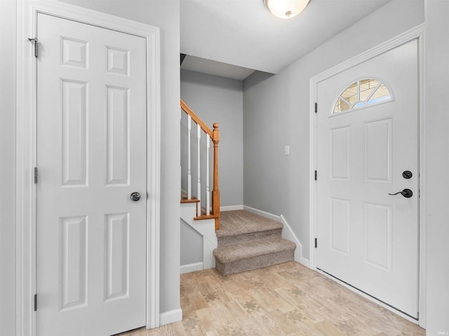foyer entrance featuring stairway, baseboards, and light wood-type flooring